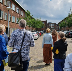 Foto van groepsexcursie tijdens de participatie-labs, deelnemers op de rug gezien, lopend door een wijk