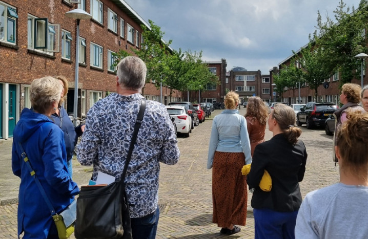 Foto van groepsexcursie tijdens de participatie-labs, deelnemers op de rug gezien, lopend door een wijk