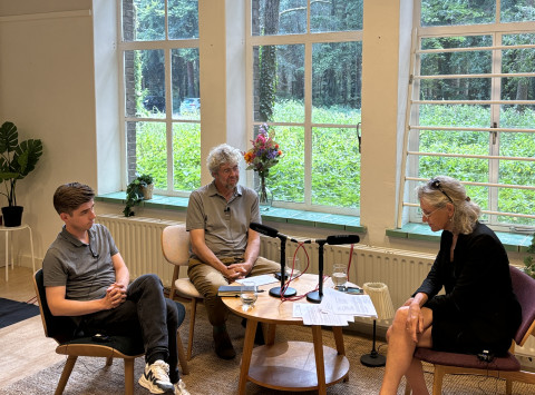 Foto van podcastopname waar de twee sprekers en interviewer in beeld zijn.