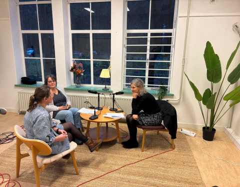Interviewsetting met Nynke de Vries, Monique Eerden en Yvonne Ploum die aan een laag tafeltje zitten en in gesprek zijn.