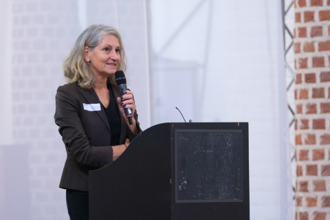 Yvonne Ploum achter een spreekgestoelte en met een microfoon in de hand