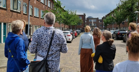 Foto van groepsexcursie tijdens de participatie-labs, deelnemers op de rug gezien, lopend door een wijk