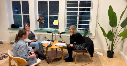 Interviewsetting met Nynke de Vries, Monique Eerden en Yvonne Ploum die aan een laag tafeltje zitten en in gesprek zijn.