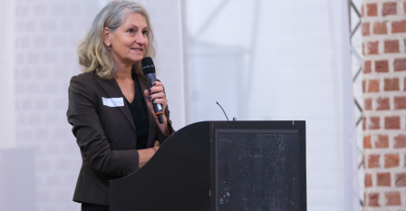 Yvonne Ploum achter een spreekgestoelte en met een microfoon in de hand